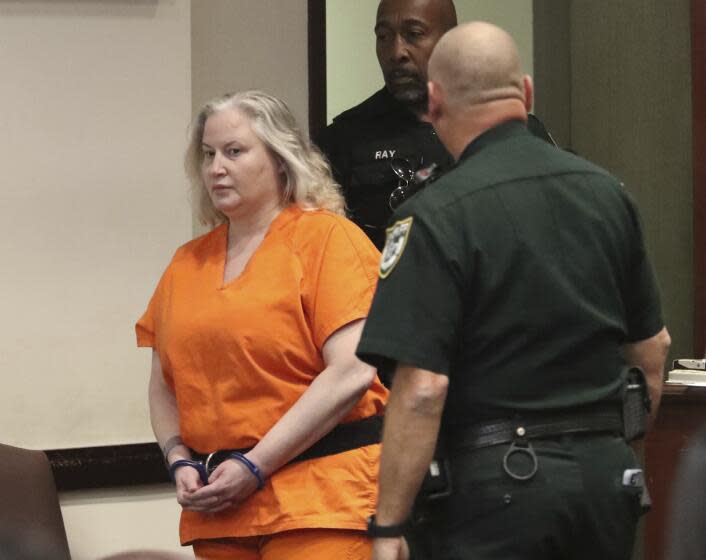 A pair of deputies walk Tammy Sytch dressed in an orange jail jumpsuit and handcuffs inside a courtroom