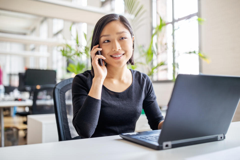 person smiling, sitting at laptop