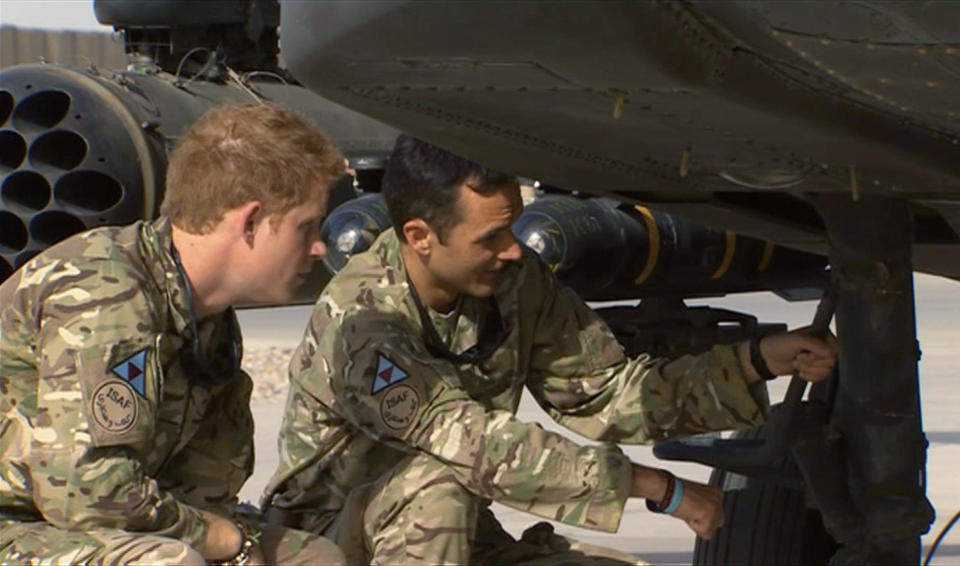 In this image from video, Britain's Prince Harry, left, has a close look at an Apache helicopter, during a tour with a member of his squadron, (name not provided) at Camp Bastion in Afghanistan, Friday Sept. 7, 2012.  Prince Harry will be based at Camp Bastion during his tour of duty as a co-pilot gunner, returning to Afghanistan to fly attack helicopters in the fight against the Taliban. (AP Photo/TV Pool)