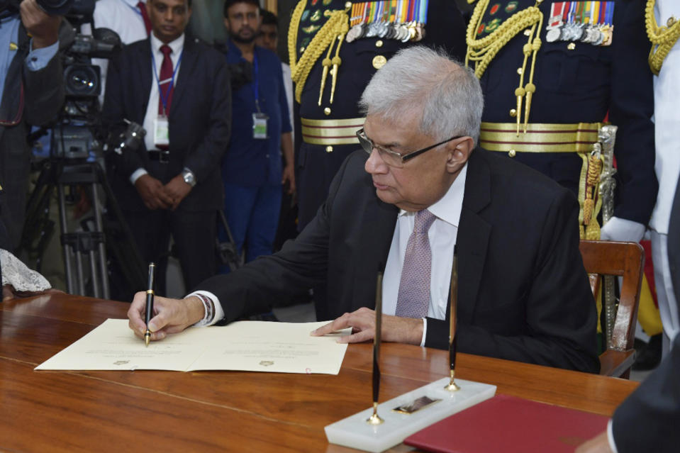 FILE - In this photo provided by Sri Lankan President's Office, Sri Lanka's newly elected president Ranil Wickremesinghe, signs after taking oath during his swearing-in ceremony in Colombo, Sri Lanka, Thursday, July 21, 2022. On Friday, he appointed a classmate and ally of ousted President Gotabaya Rajapaksa to be his prime minister and partner in rescuing the country from its predicament. The question is whether they can muster the political heft and enough support from a public fed up with shortages of food, fuel and medicine to get the job done. (Sri Lankan President's Office via AP, File)