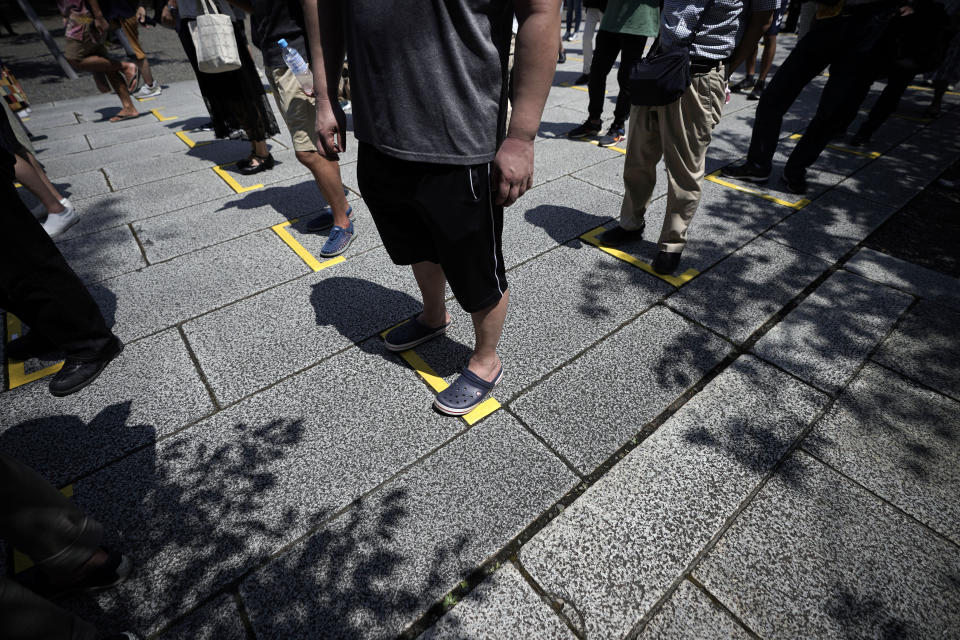 Visitors queue at intervals for social distance to prevent the spread of coronavirus at Yasukuni Shrine Saturday, Aug. 15, 2020, in Tokyo. Japan marked the 75th anniversary of the end of World War II. (AP Photo/Eugene Hoshiko)