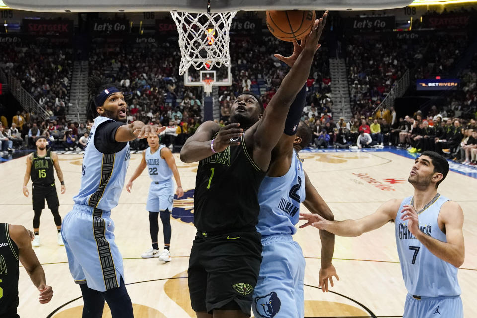 New Orleans Pelicans forward Zion Williamson (1) drives to the basket between Memphis Grizzlies forward Ziaire Williams and forward Xavier Tillman in the first half of an NBA basketball game in New Orleans, Tuesday, Dec. 26, 2023. (AP Photo/Gerald Herbert)