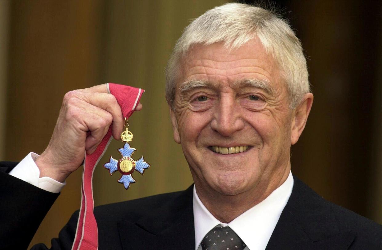 FILE - Michael Parkinson poses for the media after being awarded a CBE at Buckingham Palace in London, Nov. 24, 2000. Michael Parkinson, the renowned British broadcaster who interviewed everyone from Muhammed Ali, David Bowie and Miss Piggy, has died. He was 88. In a statement Thursday, Aug. 17, 2023 to the BBC, his family said Parkinson died “peacefully at home last night in the company of his family.