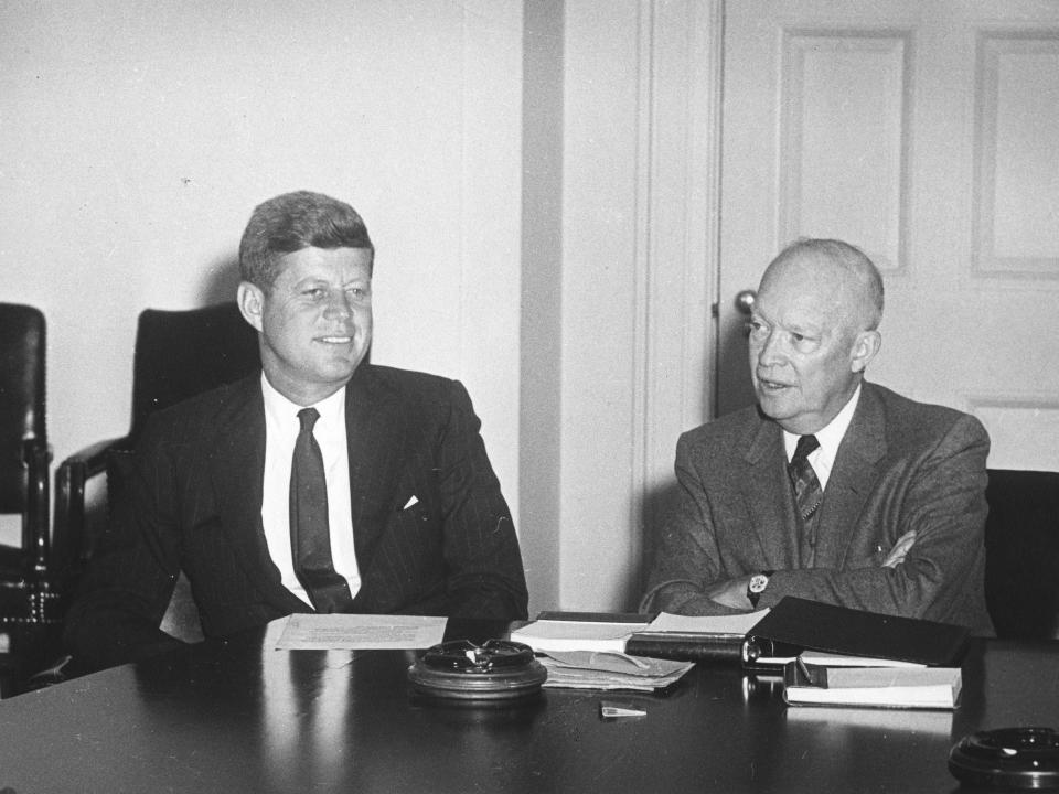 John F. Kennedy and Dwight D. Eisenhower sit at a table in Washington, DC.