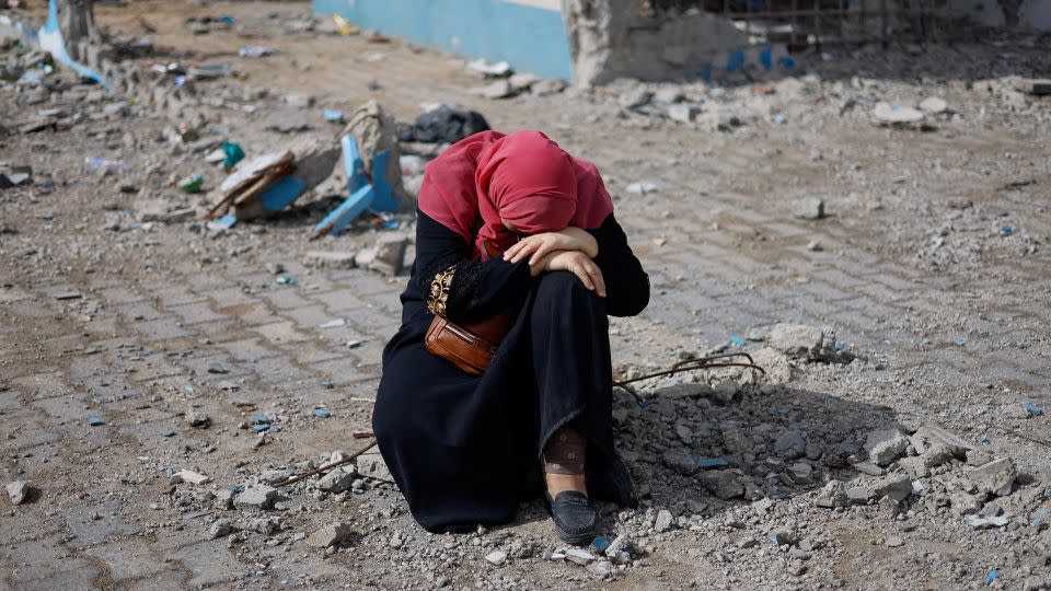 A woman rests next to a damaged building, as Palestinians arrive in Rafah after they were evacuated from Nasser hospital in Khan Younis due to the Israeli ground operation, in the southern Gaza Strip on February 15. - Mohammed Salem/Reuters