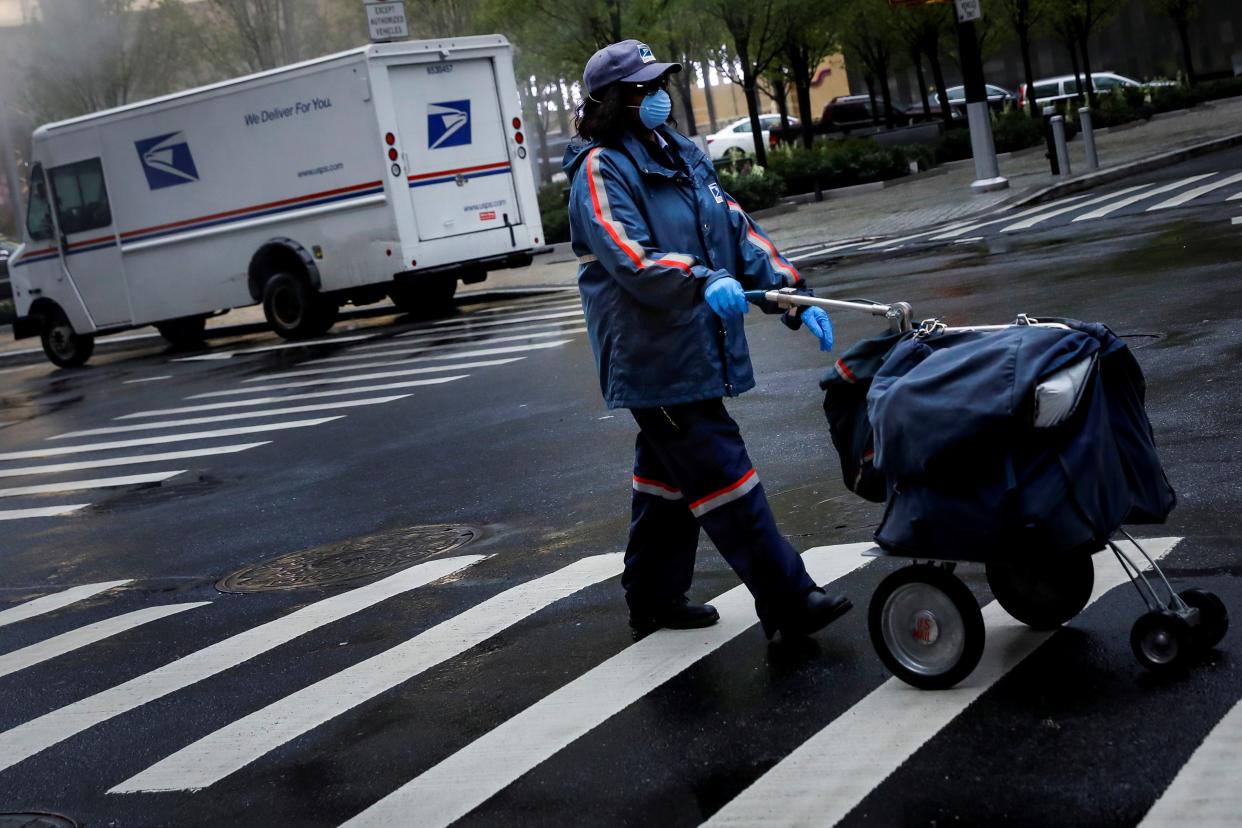 FILE PHOTO: A United States Postal Service (USPS) worker works in the rain in Manhattan during the outbreak of the coronavirus disease (COVID-19) in New York City, New York, U.S., April 13, 2020. REUTERS/Andrew Kelly