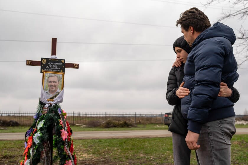 Yura Nechyporenko, 15, hugs his uncle Andriy Nechyporenko above the grave of his father Ruslan Nechyporenko