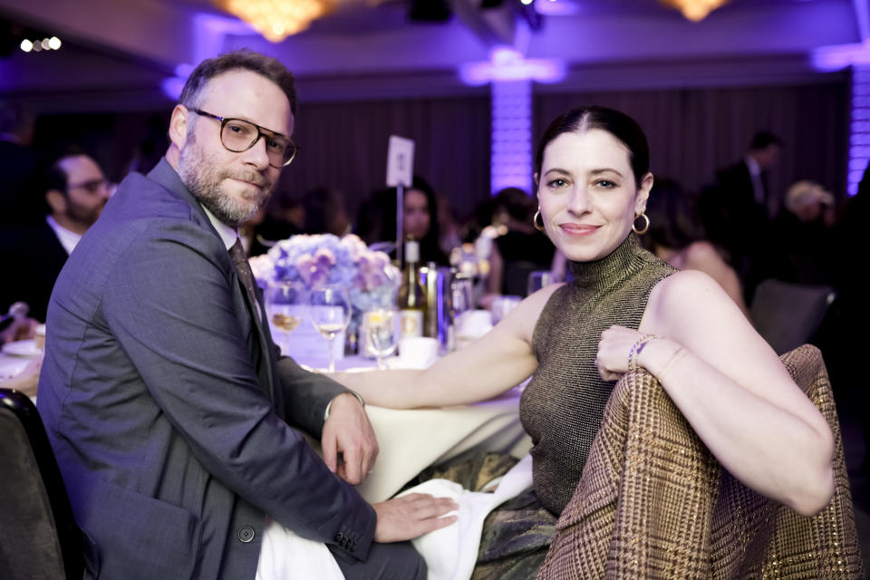 Seth and Lauren smile for a photo as they sit at a dinner table during an event