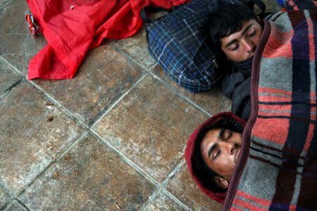 Refugees and migrants try to warm themselves up as they take a break at a petrol station before abandoning their trek to the Hungarian border, in the town of Indjija, Serbia October 5, 2016. REUTERS/Marko Djurica