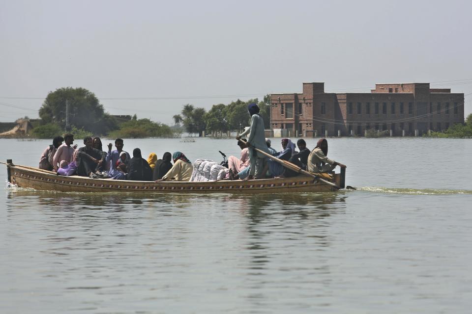 Aldeanos viajan en un bote por zonas inundadas de Dadu, localidad del sur de Pakistán muy afectada por las lluvias monzónicas. Foto del 23 de septiembre del 2022. (AP Photo/Fareed Khan)