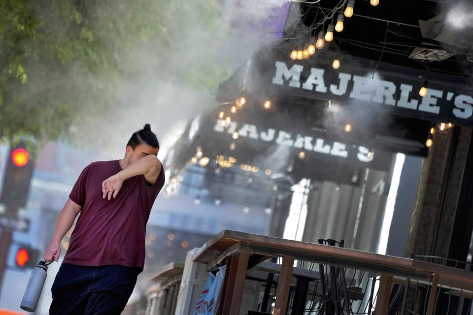 A man wipes his brow as he walks under misters, Thursday, July 13, 2023 in downtown Phoenix. The European climate agency calculates that November, for the sixth month in a row, the globe set a new monthly record for heat, adding the hottest autumn to the broken records of record-breaking heat this year. (AP Photo/Matt York)