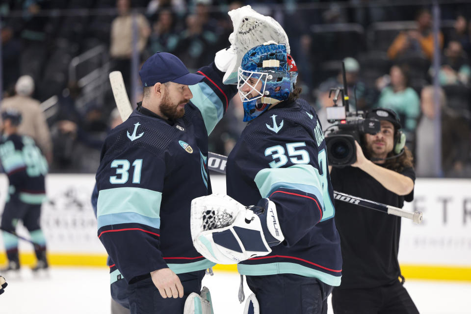 Seattle Kraken goaltender Joey Daccord (35) is congratulated by goaltender Philipp Grubauer (31) after the team's NHL hockey game against the Chicago Blackhawks on Wednesday, Jan. 24, 2024, in Seattle. The Kraken won 6-2. (AP Photo/Jason Redmond)