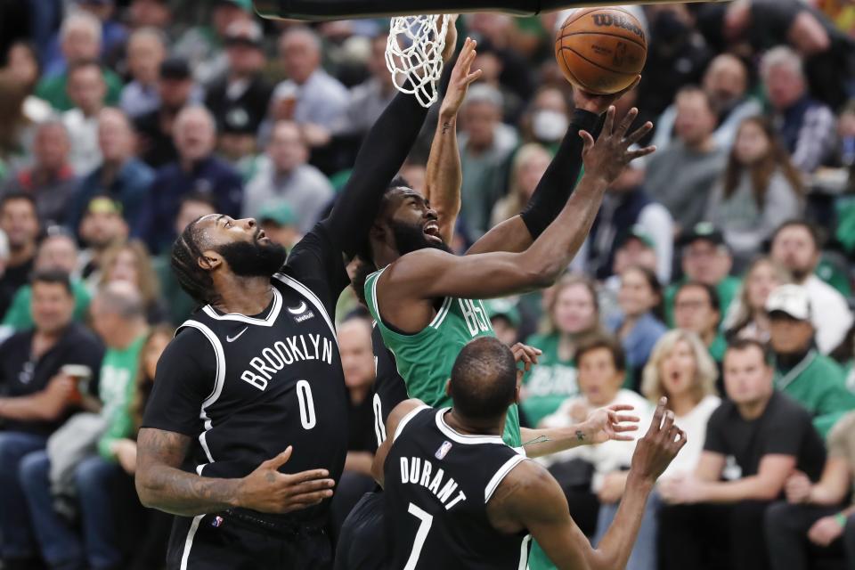 Boston Celtics' Jaylen Brown, top right, shoots against Brooklyn Nets' Andre Drummond (0) and Kevin Durant (7) during the first half of Game 2 of an NBA basketball first-round Eastern Conference playoff series Wednesday, April 20, 2022, in Boston. (AP Photo/Michael Dwyer)