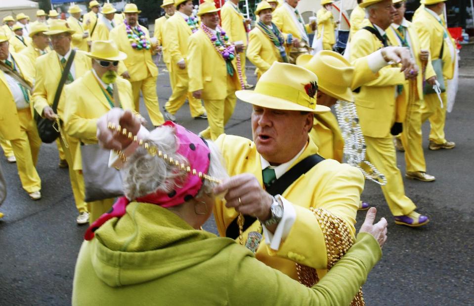 A member of Pete Fountain's Half Fast Marching Club hands out beads as the club begins it's traditional parade through the streets of New Orleans, Tuesday, Feb. 21, 2012.  This is the last day of the Mardi Gras celebration ending at midnight, after a day long celebration of parades, marching groups and people in costumes. (AP Photo/Bill Haber)