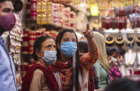 Indians wearing masks as a precaution against the coronavirus shop for bangles ahead of Hindu festivals in Jammu, India, Sunday, Oct.25, 2020. Weeks after India fully opened up from a harsh lockdown and began to modestly turn a corner by cutting new coronavirus infections by near half, a Hindu festival season is raising fears that a fresh surge could spoil the hard-won gains. (AP Photo/Channi Anand)