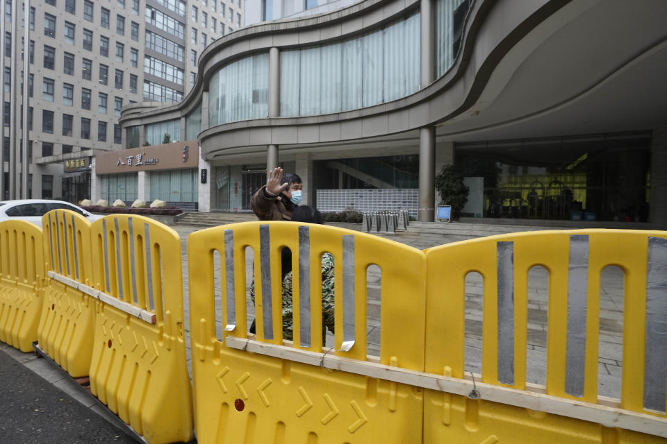 A security person waves away journalists outside the hotel where a team of experts from the World Health Organization are quarantined in Wuhan in centra China's Hubei province on Thursday, Jan. 28, 2021. A World Health Organization team has emerged from quarantine in the Chinese city of Wuhan to start field work in a fact-finding mission on the origins of the virus that caused the COVID-19 pandemic.(AP Photo/Ng Han Guan)