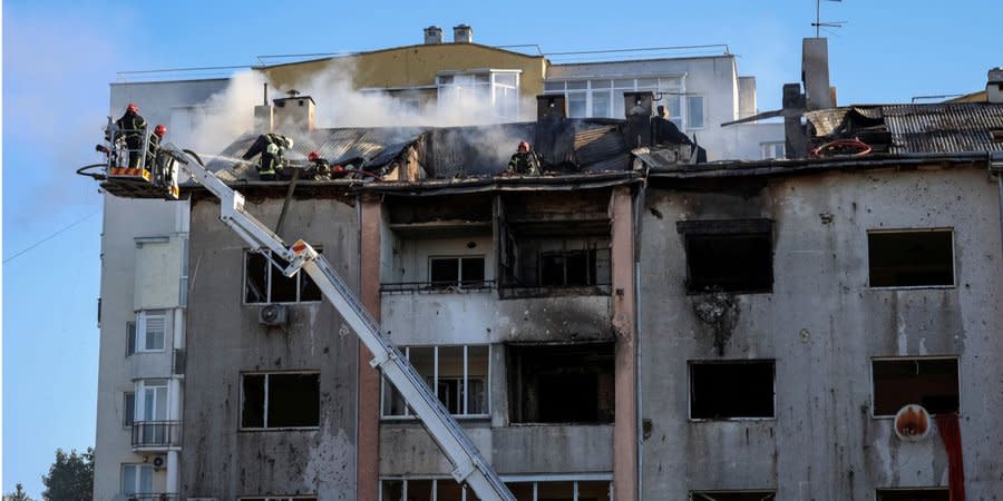 Rescuers extinguish a fire on the roof of a residential building damaged as a result of a Russian missile attack