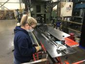 An operator checks a part dimension on a metal storage cabinet component at Tennsco's factory in Dickson