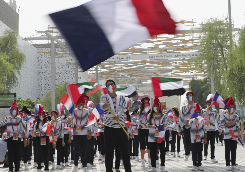 Marchers wave the French and Emirati flags during the French ceremonial day at the Dubai Expo 2020 in Dubai, United Arab Emirates, Saturday, Oct, 2, 2021. (AP Photo/Kamran Jebreili)