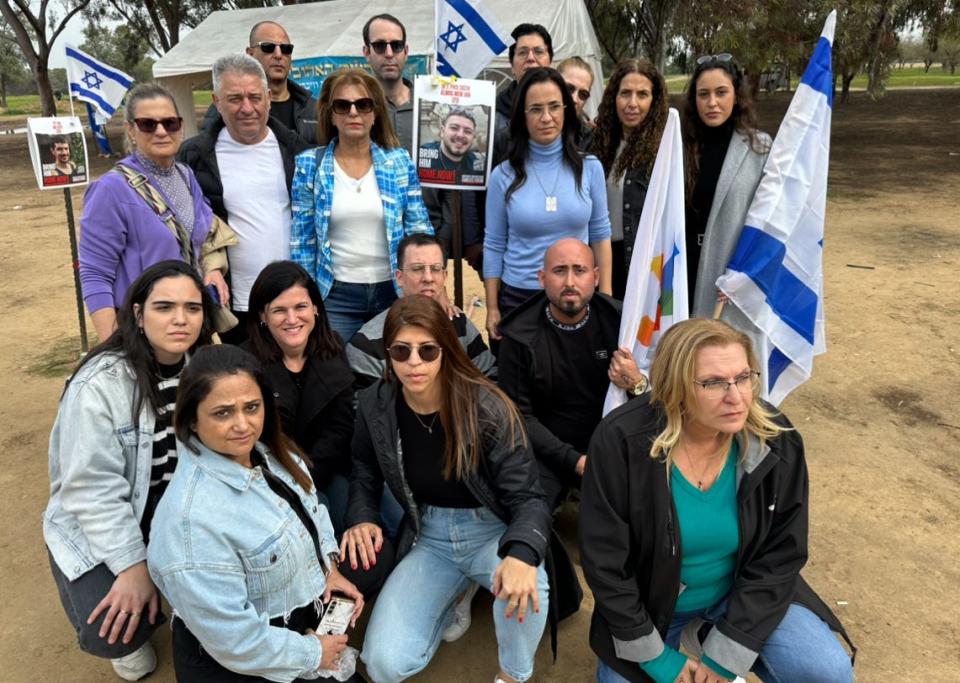 A group from the town of Or Yehuda, near Tel Aviv, gather around a poster of native son Almog Meir at the Nova site. He is among the kidnapped.