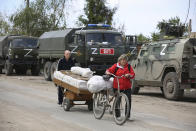 Local residents walk past Russian military vehicles in Mariupol, in territory under the government of the Donetsk People's Republic, eastern Ukraine, Tuesday, May 17, 2022. (AP Photo/Alexei Alexandrov)