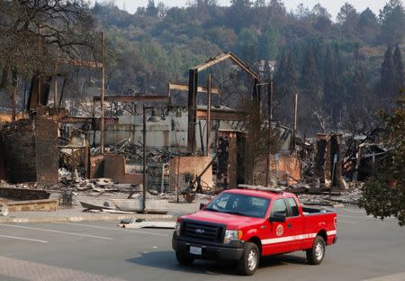 A firefighting crew drives pass a business destroyed in wildfire that tore through Santa Rosa, California, U.S., October 15, 2017. REUTERS/Jim Urquhart