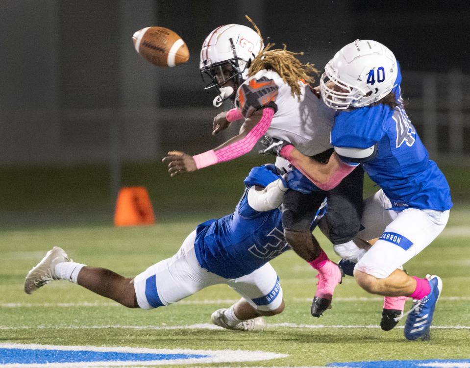 Quarterback Jakeem Tanelus of Lely fumbles as he is hit by Bolton Jackson, right, and Emmanual Rivera-Ocasio of Barron Collier during the game at Barron Collier High Friday night, October 21, 2022.