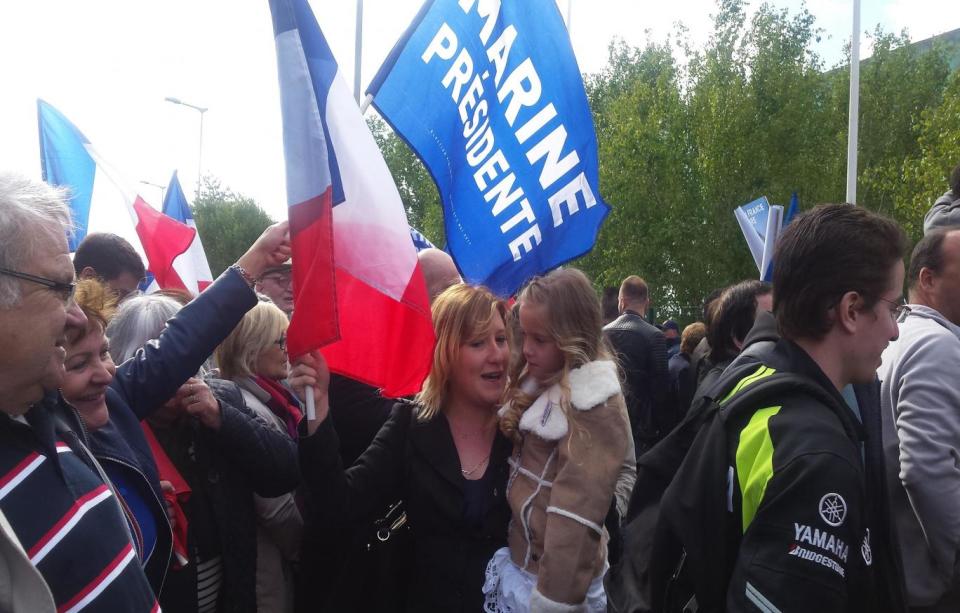 A Marine Le Pen supporter holds her daughter at Marine Le Pen's rally (The Independent)