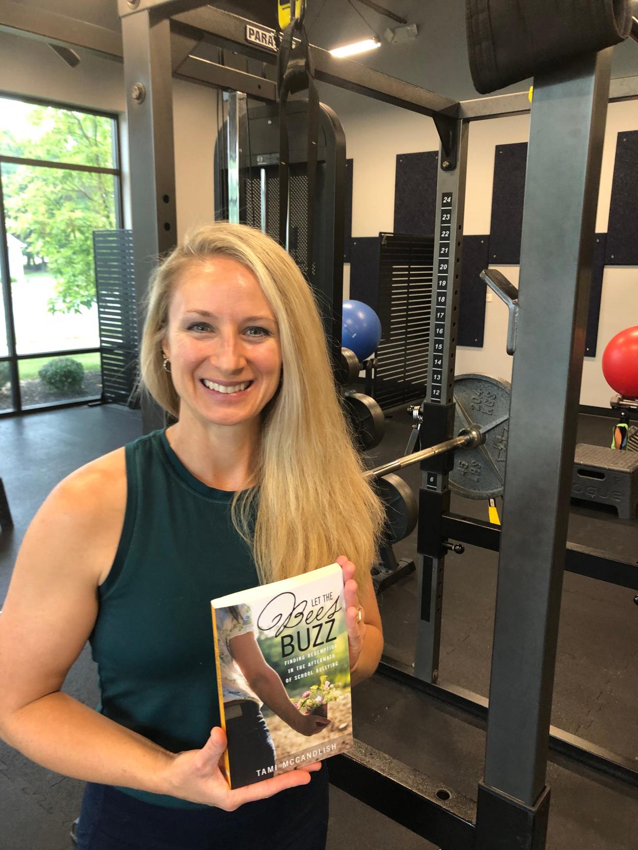 Tami McCandlish holds her book, Let the Bees Buzz: Finding Redemption in the Aftermath of School Bullying, inside the Elite Performance Newark studio she runs with her husband, Charlie Smith.