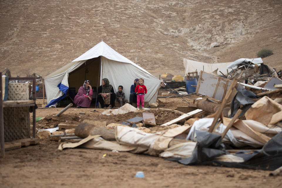 Palestinian women and children sit front a tent in Khirbet Humsu in Jordan Valley in the West Bank, Friday, Nov. 6, 2020. Israeli troops with bulldozers and heavy equipment demolished 18 tents and other structures that housed 74 people, including 41 minors, according to the Israeli rights group B'Tselem. COGAT, the Israeli military body in charge of civilian affairs in the West Bank, said an "enforcement activity" was carried out against seven tents and eight pens that were "illegally constructed" in a firing range. (AP Photo/Majdi Mohammed)