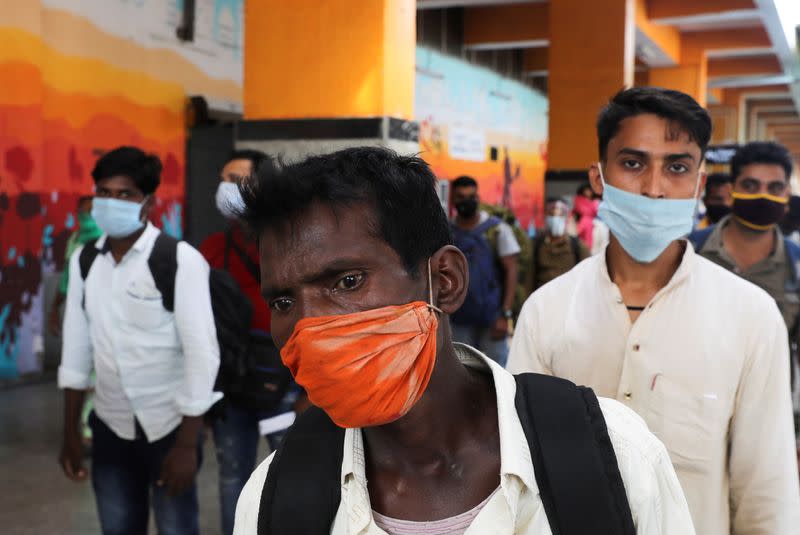 Passengers wearing protective face masks stand in a queue on a platform to get tested for the coronavirus disease (COVID-19), at a railway station, in New Delhi