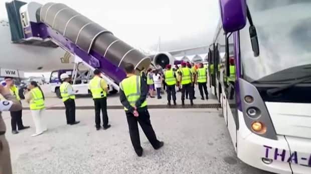 Emergency personnel and airport staff stand near the plane after it made an emergency landing at Suvarnabhumi airport in Bangkok. 