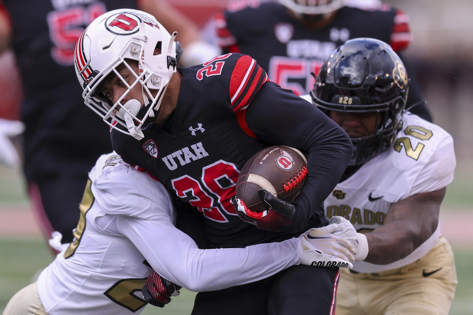 Utah running back Sione Vaki (28) is tackled by Colorado linebacker Demouy Kennedy (22) and linebacker LaVonta Bentley (20) during the first half of an NCAA college football game Saturday, Nov. 25, 2023, in Salt Lake City. (AP Photo/Rob Gray)