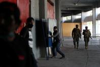 Soldiers patrol as workers carry voting booth sections inside a polling station ahead of the upcoming referendum on a new Chilean constitution in Santiago