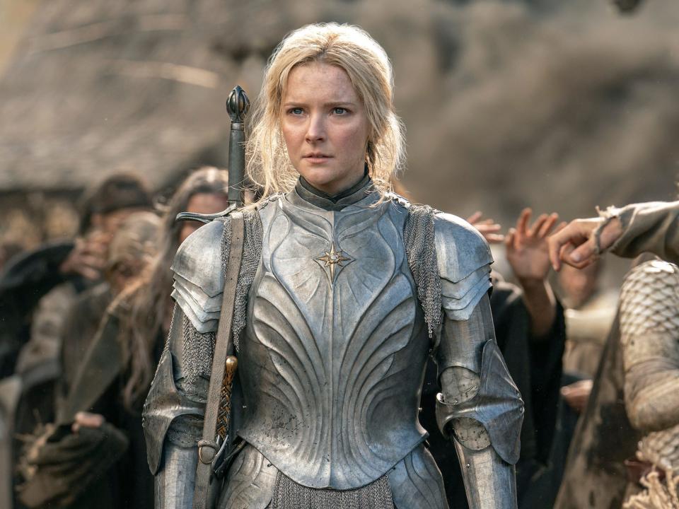 A woman with blonde hair wearing silver army on a battlefield.