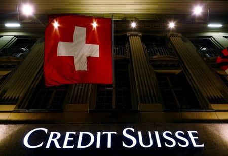 The logo of Swiss bank Credit Suisse is seen below the Swiss national flag at a building in the Federal Square in Bern, Switzerland, May 15, 2014. REUTERS/Ruben Sprich/File Photo