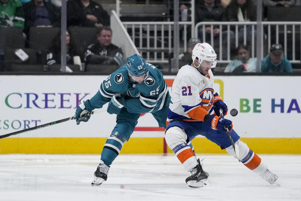 San Jose Sharks defenseman Erik Karlsson, left, and New York Islanders center Kyle Palmieri compete for possession of the puck during the second period of an NHL hockey game in San Jose, Calif., Saturday, March 18, 2023. (AP Photo/Godofredo A. Vásquez)