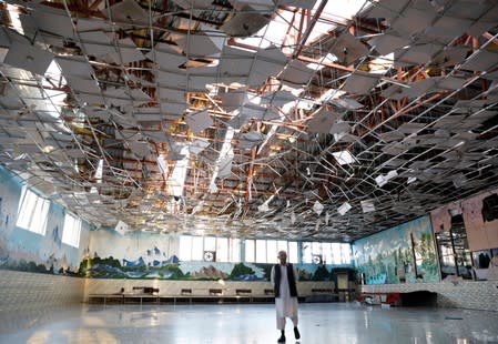 An Afghan man inspects a damaged wedding hall after a blast in Kabul, Afghanistan