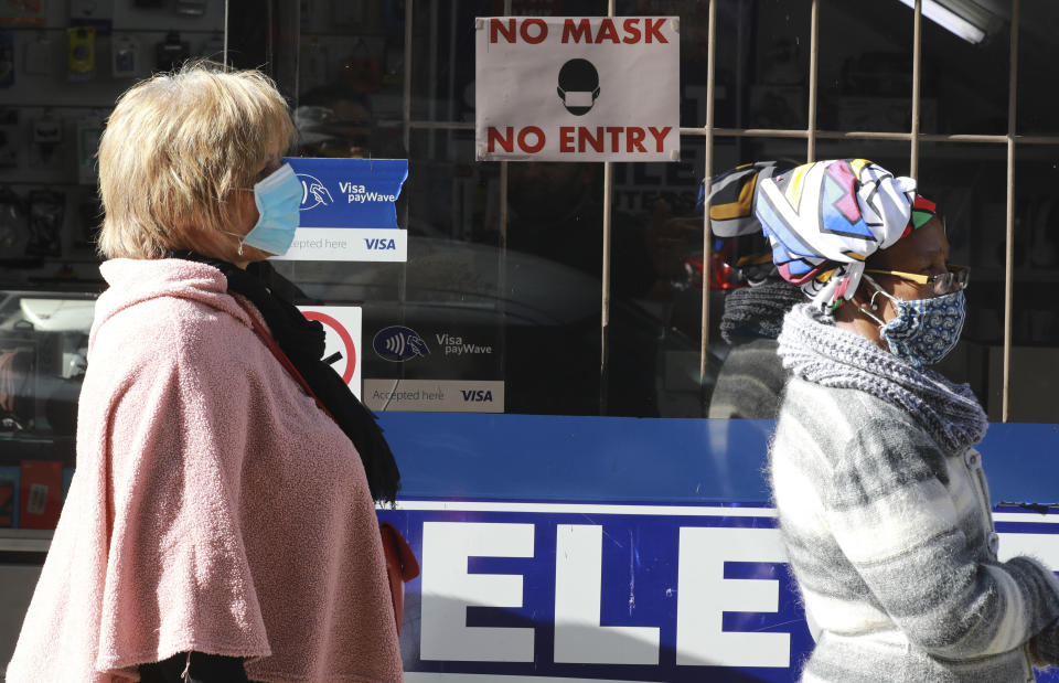 People wearing face masks queue at a South African Social Security Agency (SASSA) to collect their government grant in Cape Town South Africa, Monday, May 11, 2020. South Africa's Western Cape province, which includes the city of Cape Town, has emerged as the country's coronavirus hotspot, accounting for more than half of the nation's confirmed cases, which have gone above 10,000.(AP Photo/Nardus Engelbrecht)