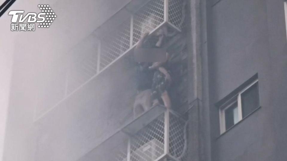 住戶爬出鐵窗外求救。（圖／TVBS）