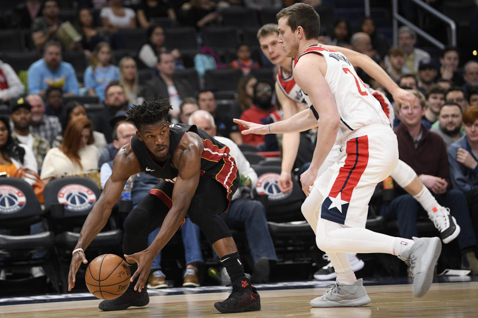 Miami Heat forward Jimmy Butler, left, grabs the ball next to Washington Wizards guard Garrison Mathews, right, during the first half of an NBA basketball game, Sunday, March 8, 2020, in Washington. (AP Photo/Nick Wass)