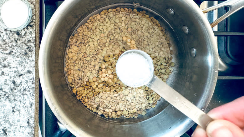 hand adding salt to lentils