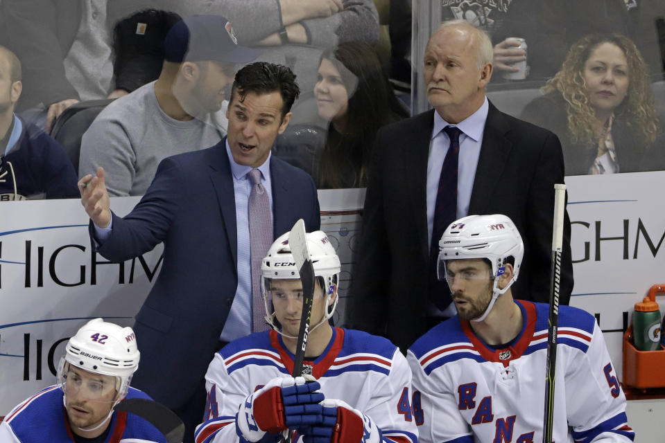 FILE - In this Feb. 17, 2019, file photo, New York Rangers head coach David Quinn, standing at left, talks with assistant Lindy Ruff, standing at right, during the first period of an NHL hockey game against the Pittsburgh Penguins, in Pittsburgh. A person with knowledge of the talks tells The Associated Press that the New Jersey Devils are hiring veteran coach Lindy Ruff to take over one of the NHL’s youngest teams and removing the interim tag off Tom Fitzgerald’s title as general manager. (AP Photo/Gene J. Puskar, File)