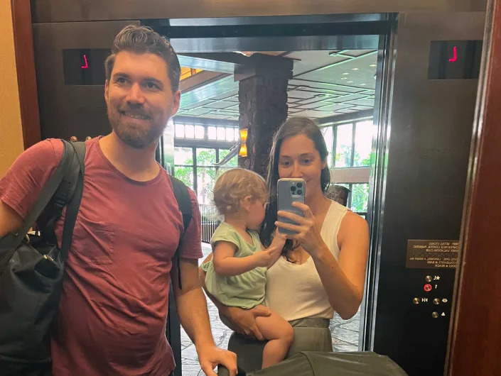A family taking a selfie with a baby in an elevator.