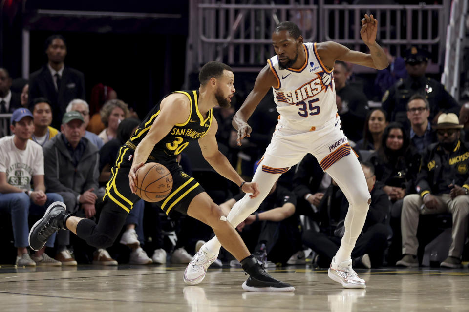 Golden State Warriors guard Stephen Curry (30) drives to the basket against Phoenix Suns forward Kevin Durant (35) during the first half of an NBA basketball game in San Francisco, Saturday, Feb. 10, 2024. (AP Photo/Jed Jacobsohn)