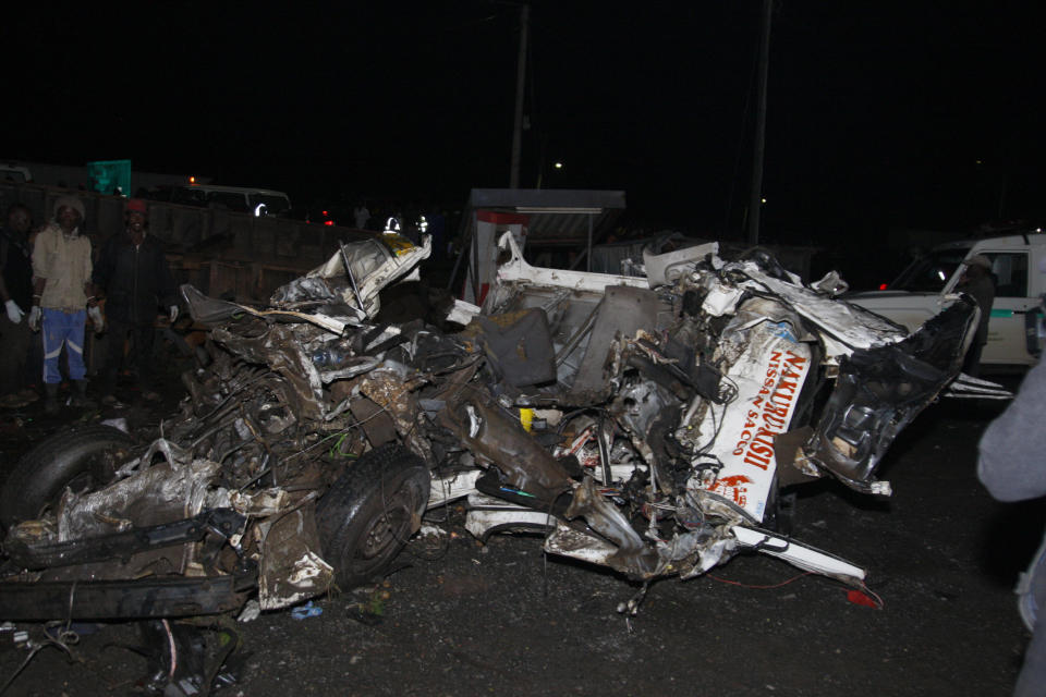 CORRECTS DATE - People stand near the wreckage of vehicles after a fatal accident in Londiani, Kenya, Friday, June 30, 2023, at a location known for crashes about 200 kilometers (125 miles) northwest of the capital, Nairobi. Dozens were killed when a truck rammed into several other vehicles and market traders on Friday evening, police said. (AP Photo)