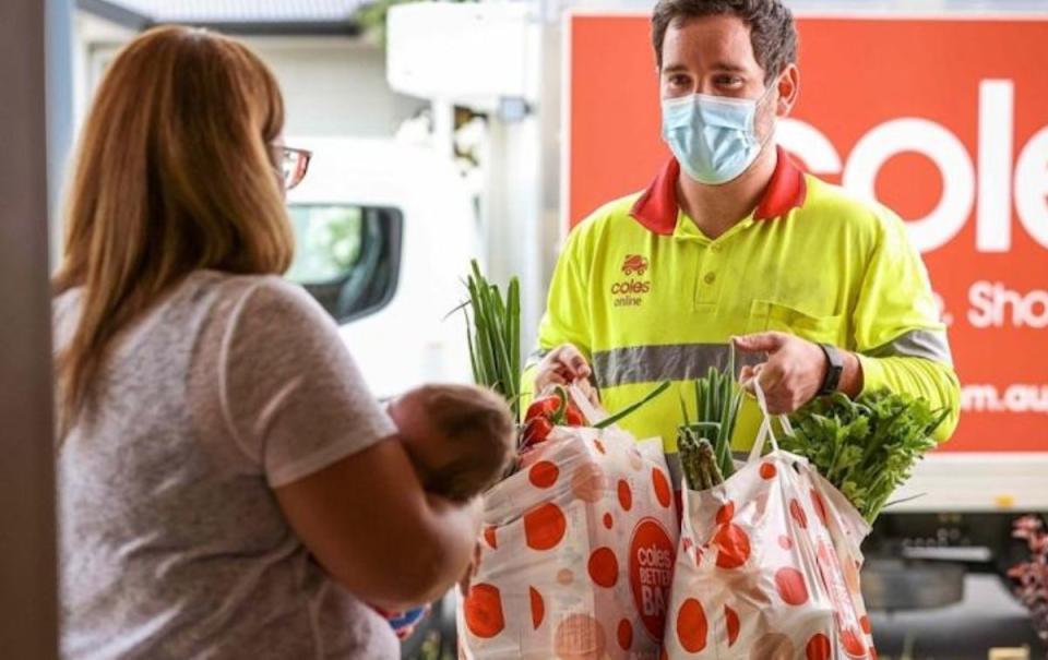 Coles delivery driver delivering groceries to woman with baby. Source: Coles