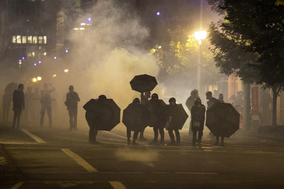 FILE - In this Sept. 18, 2020, file photo, tear gas fills the air during protests in Portland, Ore. An Oregon lawmaker is seeking to ban the use of tear gas and other agents against crowds of people in one of the most sweeping police measures in the country regarding crowd control devices. (AP Photo/Paula Bronstein, File)
