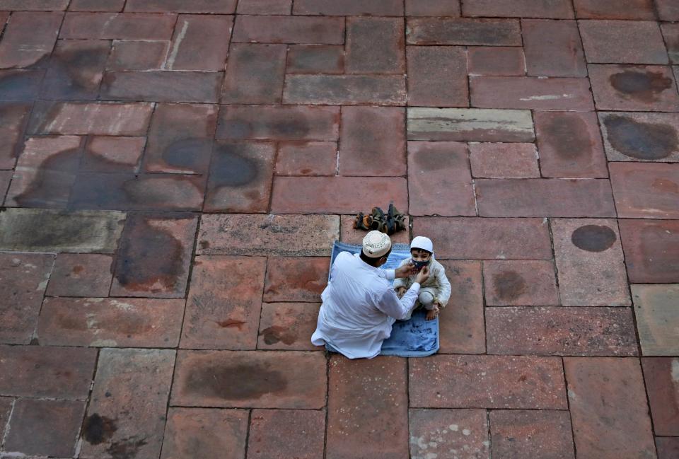 An Indian Muslim adjusts the mask of his son as they wait to offer Eid al-Adha prayer at the Jama Masjid in New Delhi, India, Saturday, Aug.1, 2020. Muslims worldwide marked the the Eid al-Adha holiday over the past days amid a global pandemic that has impacted nearly every aspect of this year's celebrations. (AP Photo/Manish Swarup)