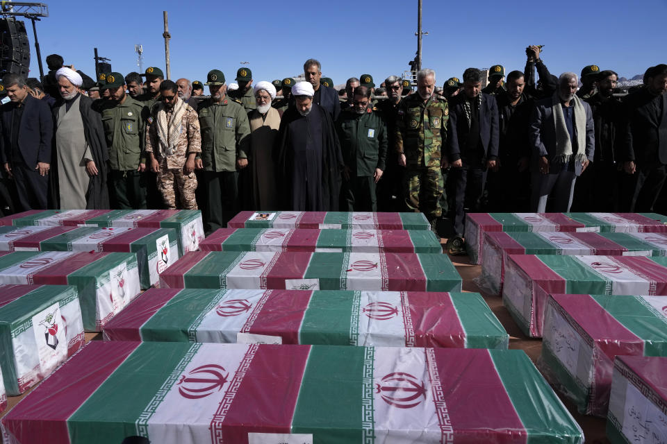 People pray over the flag-draped coffins of victims of Wednesday's bomb explosion during their funeral ceremony in the city of Kerman about 510 miles (820 kms) southeast of the capital Tehran, Iran, Friday, Jan. 5, 2024. Iran on Friday mourned those slain in an Islamic State group-claimed suicide bombing targeting a commemoration for a general slain in a U.S. drone strike in 2020. (AP Photo/Vahid Salemi)